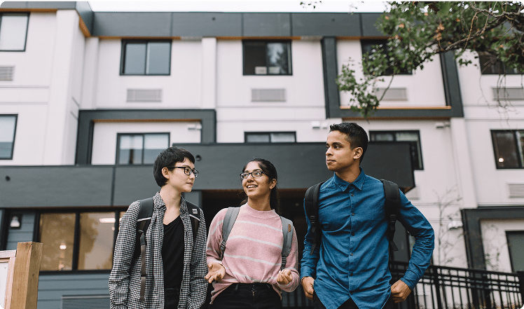 Young people smiling in front of a building.