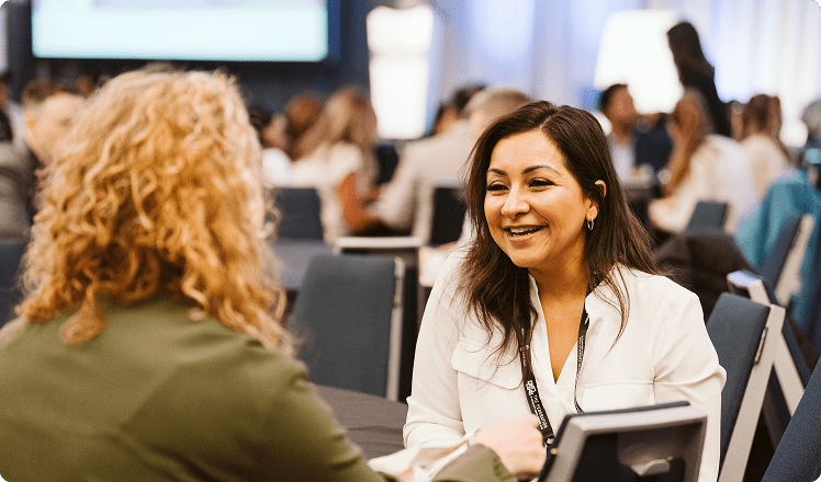 A woman speaking to another woman at an HCC event. 
