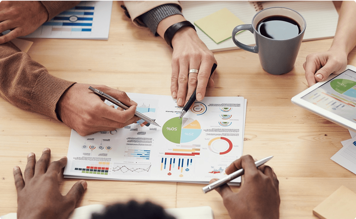 Several hands pointing and examining a bunch of graphs.