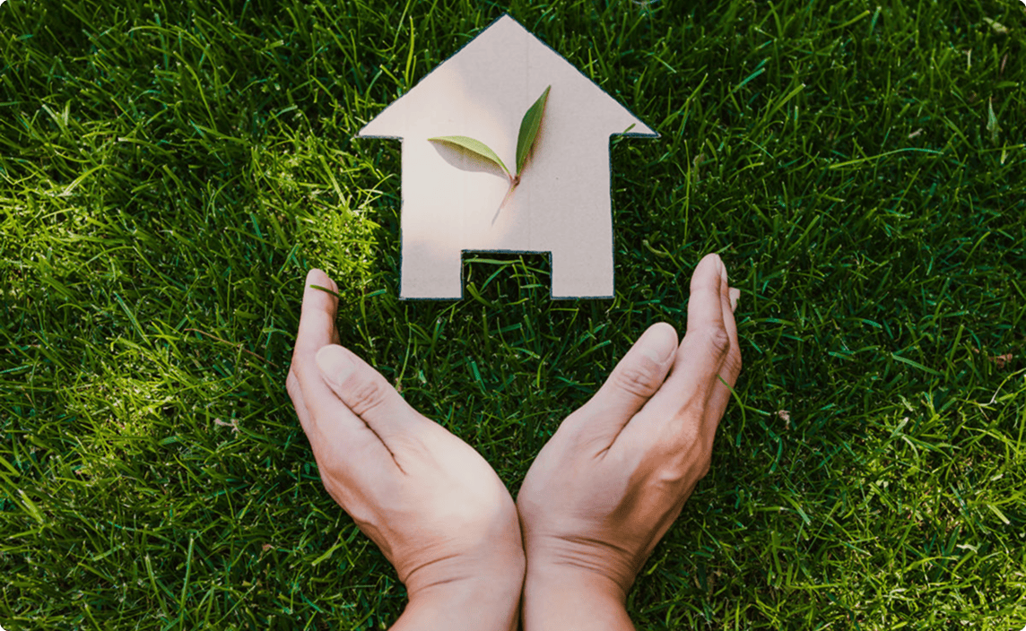 Green lawn with 2 hands framing a small wood house.