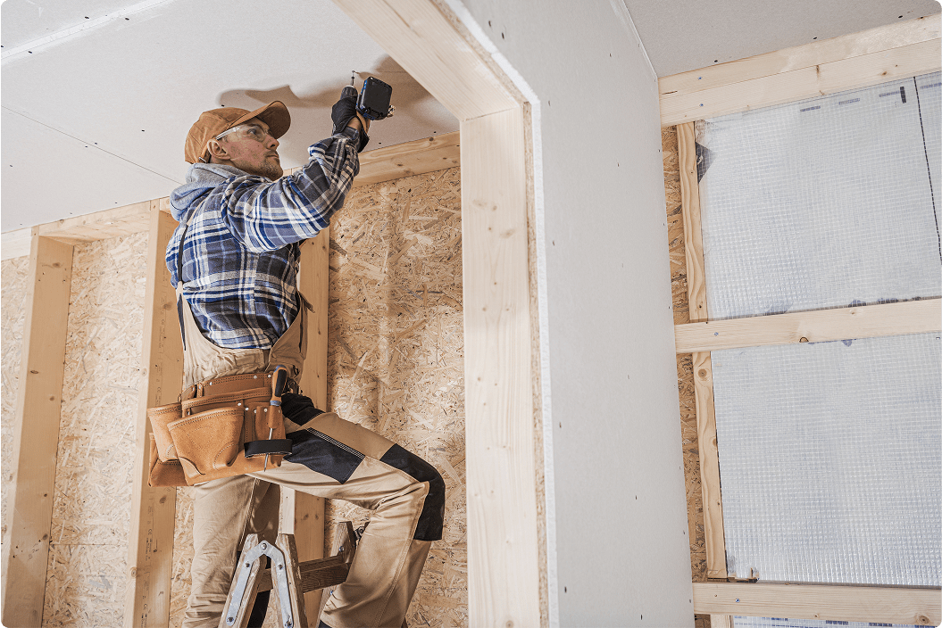 A worker applying drywall to a wall.