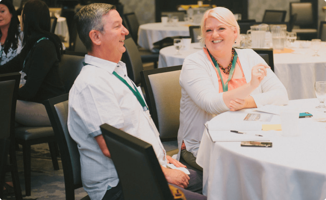 Two people chatting at a table at a conference.