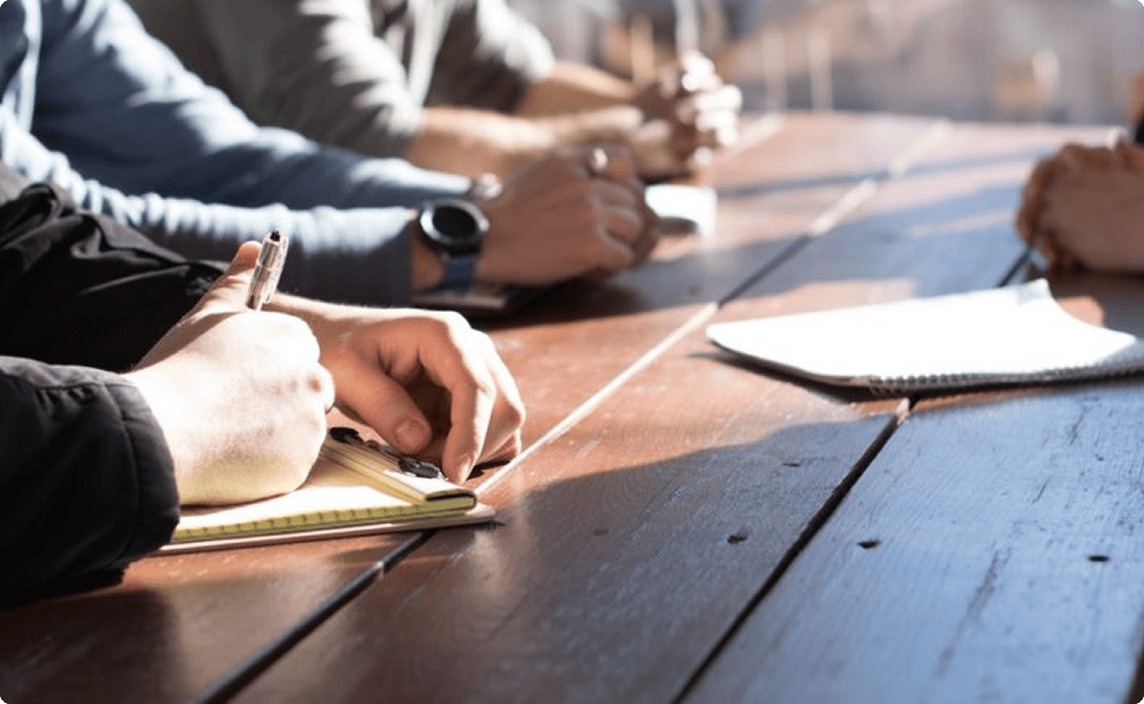 People sitting at a table writing and reviewing documents.