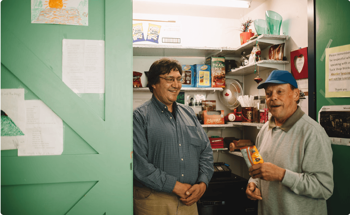 Two people laughing inside a food pantry in a shared living home.