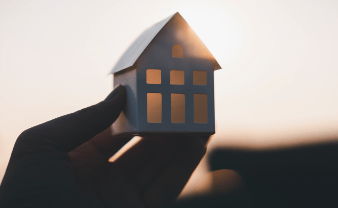 A person holding a miniature of a house.