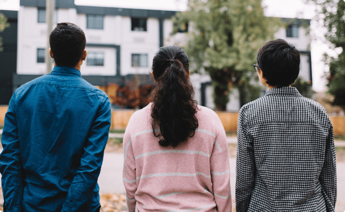Three youths looking at a row of new housing.