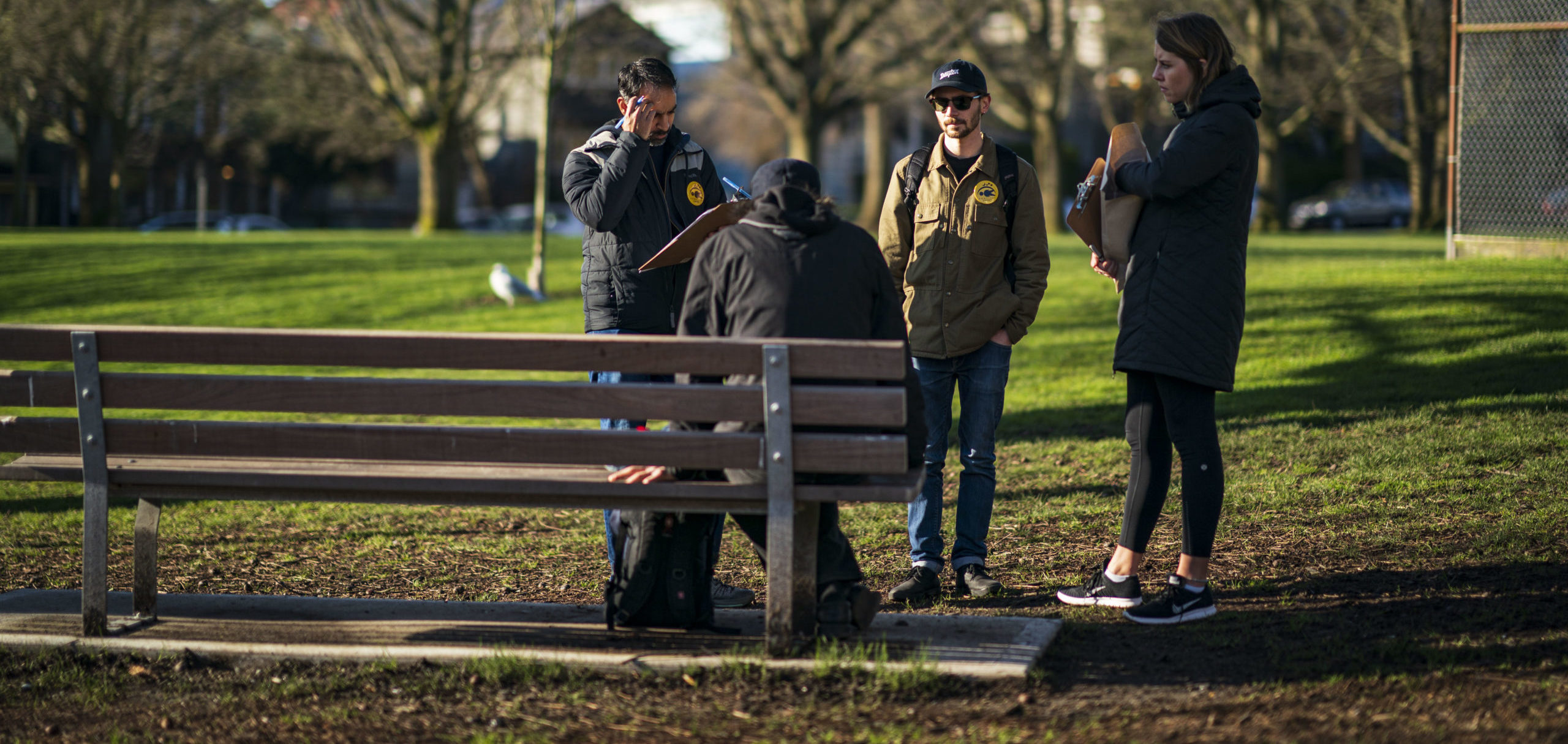 People at a bench by the park