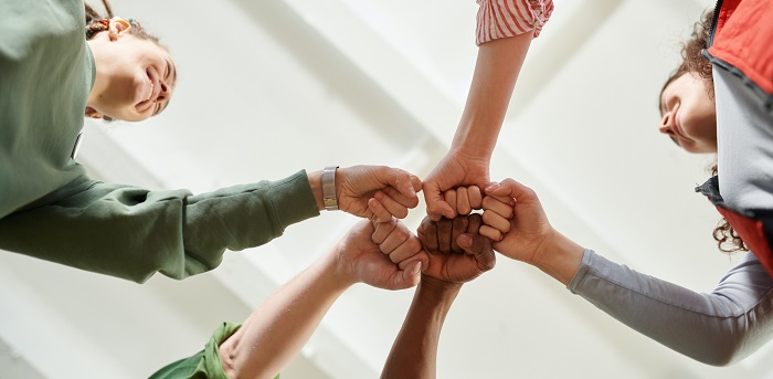 A group of people giving each other a fist bump in a circle.