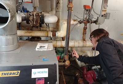 A professional inspecting a pipe in a basement.